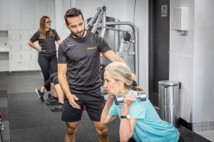 Personal Trainer Help Client Through Exercise - Edge Fit